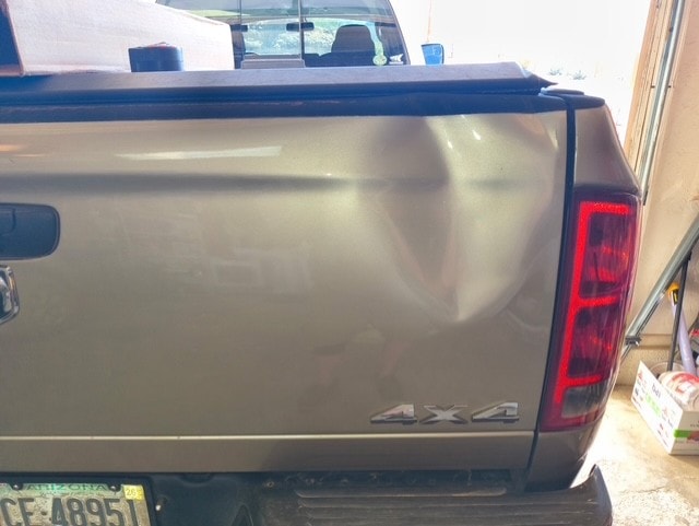 Ram 4x4 truck bed with large dent before paintless dent repair