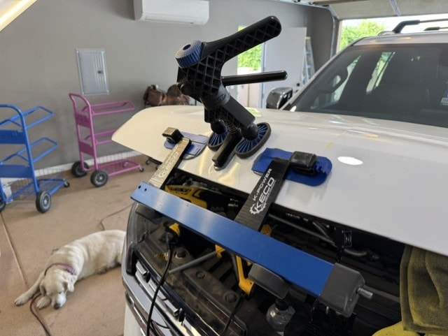 PDR glue pull tool mounted on white SUV hood in garage